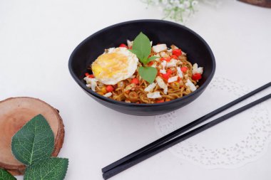 fried noodles with fried egg and vegetables as a background