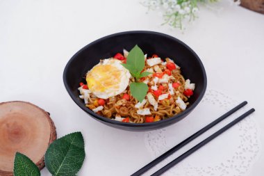 fried noodles with fried egg and vegetables as a background
