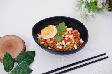 fried noodles with fried egg and vegetables as a background