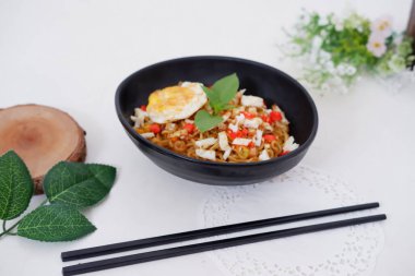 fried noodles with fried egg and vegetables as a background