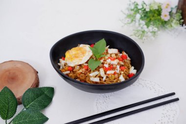 fried noodles with fried egg and vegetables as a background