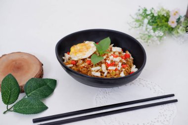 fried noodles with fried egg and vegetables as a background