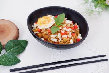 fried noodles with fried egg and vegetables as a background