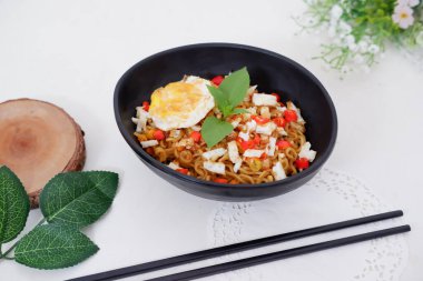 fried noodles with fried egg and vegetables as a background