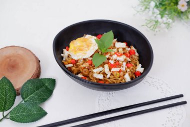 fried noodles with fried egg and vegetables as a background