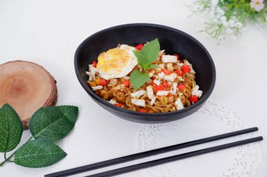 fried noodles with fried egg and vegetables as a background