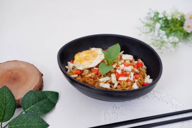 fried noodles with fried egg and vegetables as a background
