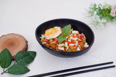 fried noodles with fried egg and vegetables as a background