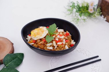 fried noodles with fried egg and vegetables as a background