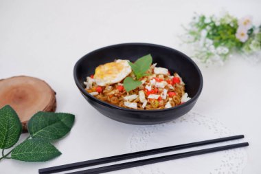 fried noodles with fried egg and vegetables as a background