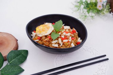 fried noodles with fried egg and vegetables as a background