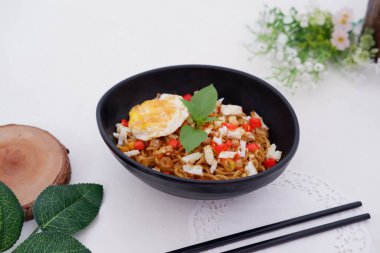 fried noodles with fried egg and vegetables as a background