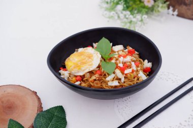 fried noodles with fried egg and vegetables as a background