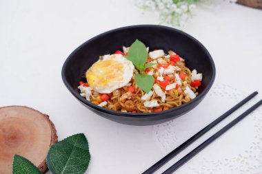 fried noodles with fried egg and vegetables as a background