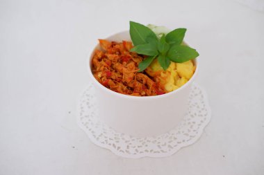 rice with sliced spicy chicken and vegetables as a background