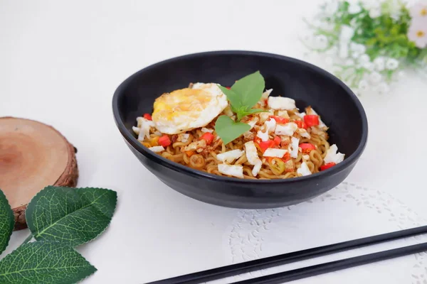 fried noodles with fried egg and vegetables as a background