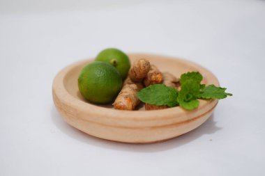 Zencefil, kireç ve nane beyaz arka planda izole edilmiş ahşap tabakta.