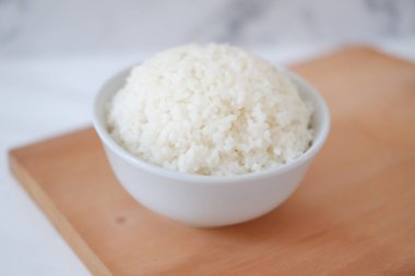 Tahta bir tahtanın üzerinde beyaz bir kasede pilav pişirdim. Seçici odak.