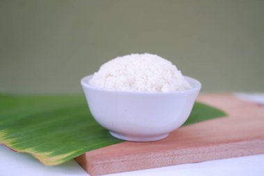 Beyaz kasedeki pirinç ahşap masada ve yeşil duvar arka planında