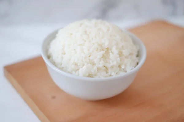 Tahta bir tahtanın üzerinde beyaz bir kasede pilav pişirdim. Seçici odak.