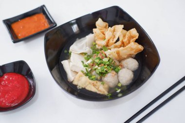 Bir kase köfte çorbası, yemek çubukları ve acı sos.