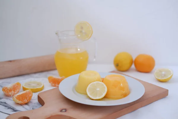 Orange jelly with fresh lemon and orange juice on a white background.