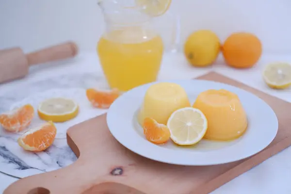 Orange jelly with fresh lemon and orange juice on a white background.