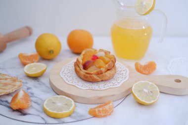 Taze meyveli ev yapımı limonlu tart ve beyaz arka planda portakal suyu.