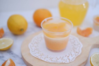 Bardakta taze portakal suyu ve beyaz arka planda taze narenciye meyvesi..