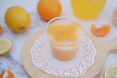 Bardakta taze portakal suyu ve beyaz arka planda taze narenciye meyvesi..