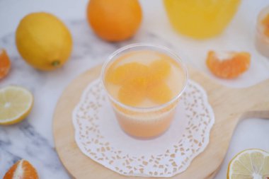 Bardakta taze portakal suyu ve beyaz arka planda taze narenciye meyvesi..