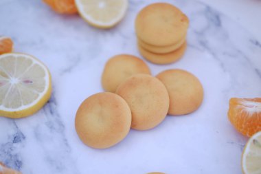 Limon, portakal ve limon dilimleri beyaz mermer bir masada..