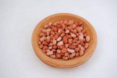 Fıstıkları beyaz arka planda tahta bir kaseye koy..