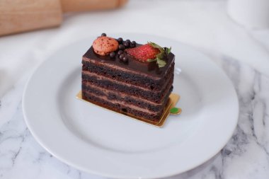 Çilekli çikolatalı kek ve beyaz tabakta badem kurabiyesi.