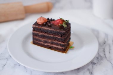 Çilekli çikolatalı kek ve beyaz tabakta badem kurabiyesi.