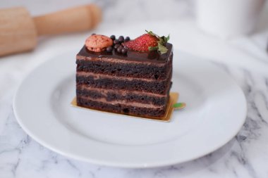 Çilekli çikolatalı kek ve beyaz tabakta badem kurabiyesi.