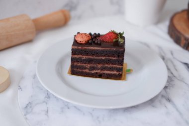 Çilekli çikolatalı kek ve beyaz tabakta badem kurabiyesi.