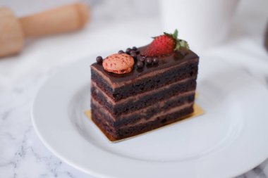 Çilekli çikolatalı kek ve beyaz tabakta badem kurabiyesi.