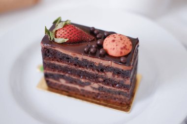 Çilekli çikolatalı kek ve beyaz tabakta badem kurabiyesi.