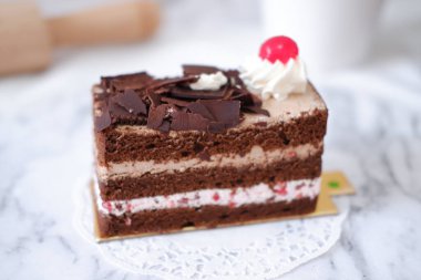 Krem şantili çikolatalı pasta ve beyaz mermer arka planda kirazlar.