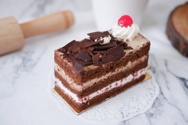 Krem şantili çikolatalı pasta ve beyaz mermer arka planda kirazlar.