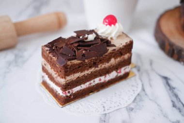 Krem şantili çikolatalı pasta ve beyaz mermer arka planda kirazlar.