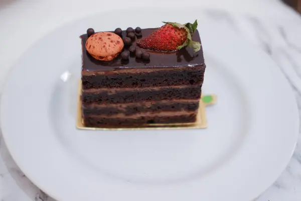 Stück Schokoladenkuchen Mit Erdbeeren Und Makronen Auf Weißem Teller — Stockfoto