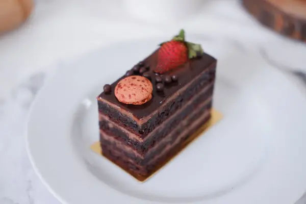 ホワイトプレートにイチゴとマカロンが付いたチョコレートケーキ — ストック写真
