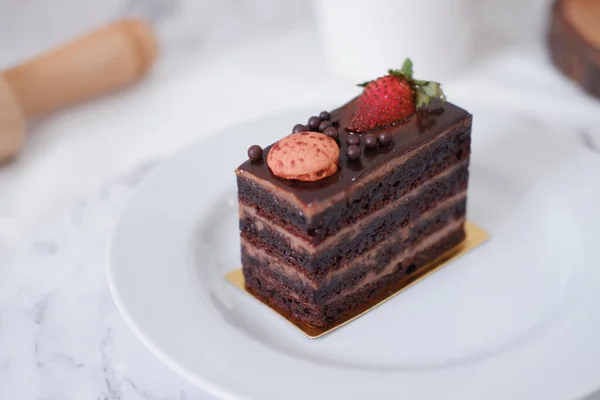 ホワイトプレートにイチゴとマカロンが付いたチョコレートケーキ — ストック写真