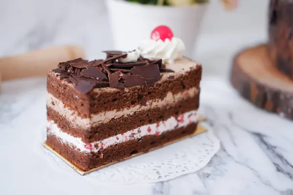 白大理石背景的带有奶油和樱桃的巧克力蛋糕 — 图库照片