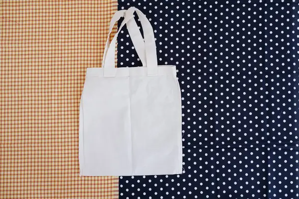 White cotton bag on a blue and white polka dot background.