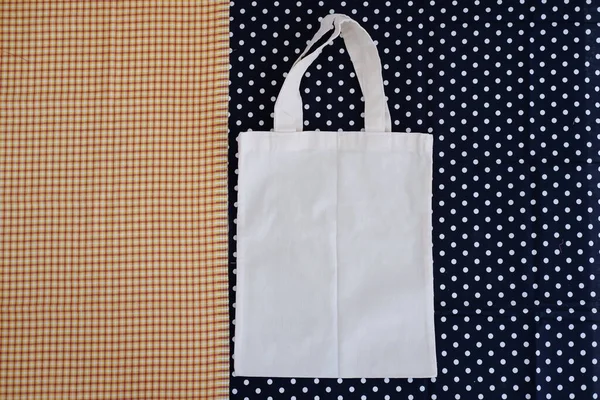 White cotton bag on a blue and white polka dot background.