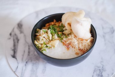 Beyaz mermer masada siyah kasede tavuklu pirinç lapası.