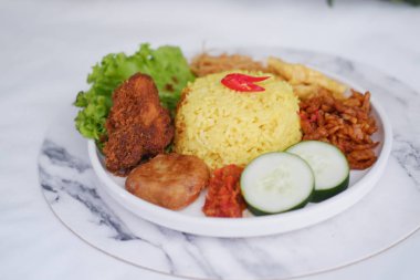 Endonezya usulü, tavuklu sarı pirinç ve beyaz tabakta garnitür.